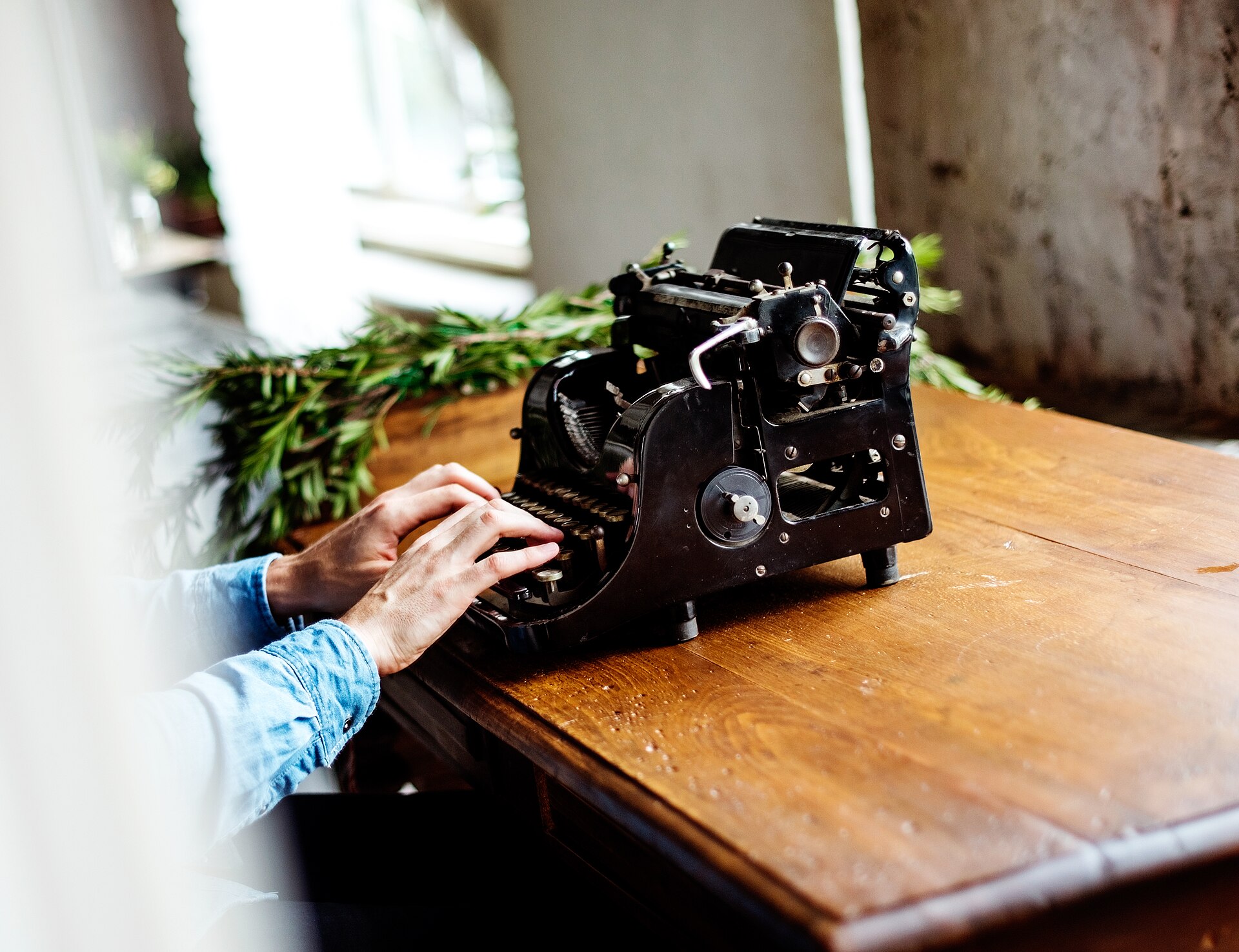 Hands typing on a manual typewriter, seen from above.